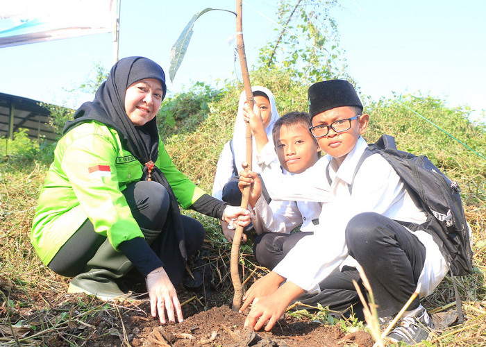 : SEJAK DINI: Kepala DLH Yuni Darti mengajak pelajar SD, menanam pohon bersama. Hal baik ini, harus ditanamkan sejak dini. Karena bumi ini, untuk generasi ke generasi. 